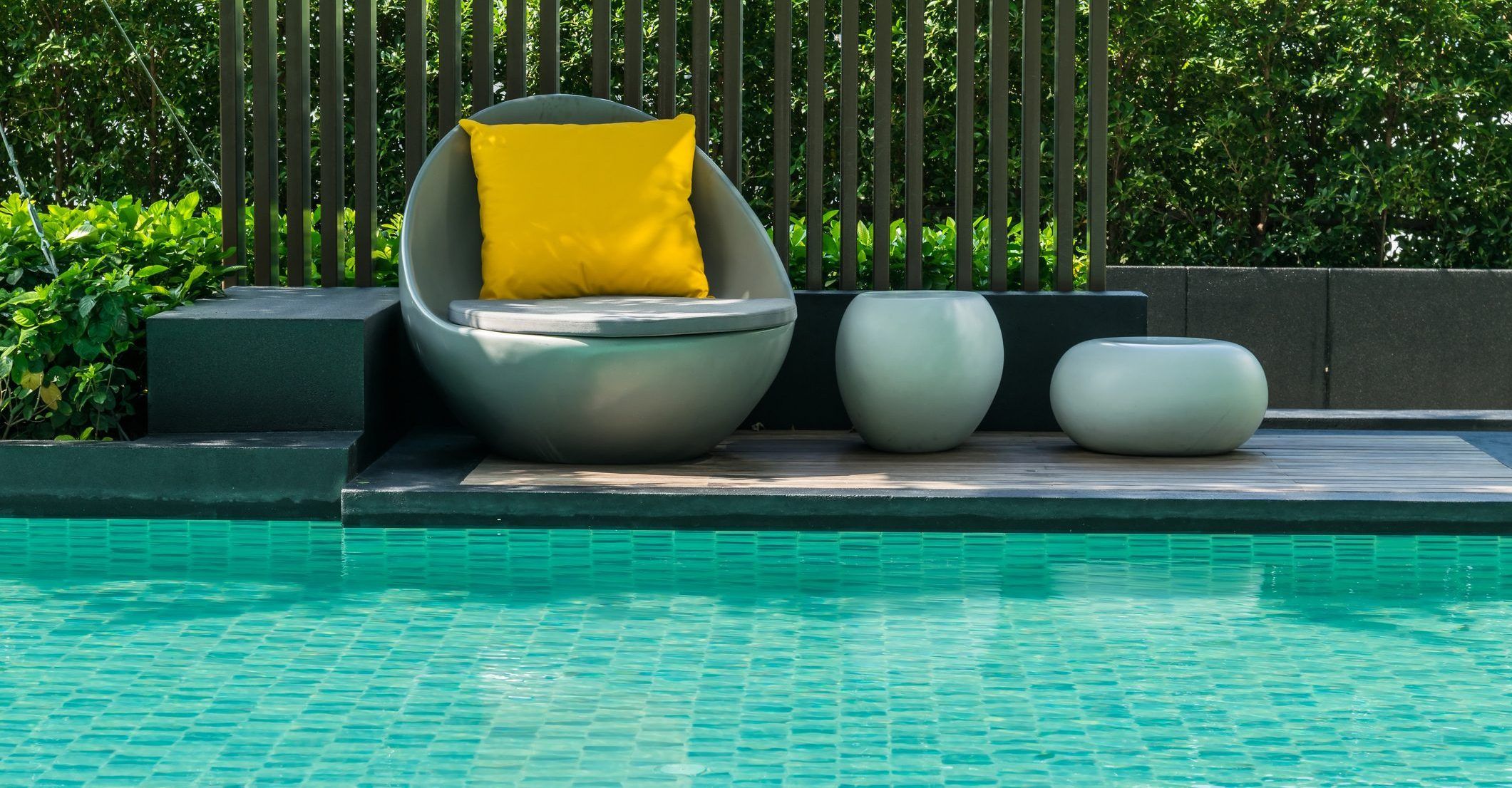 Relaxing chairs with pillows beside swimming pool